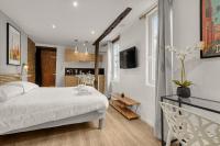 a bedroom with a white bed and a kitchen at Le Studio des Antiquaires - Studio climatisé in Toulouse