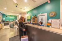 a woman with a suitcase standing at a counter in a store at Break &amp; Home Paris Italie Porte de Choisy in Ivry-sur-Seine