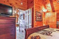 ein Schlafzimmer mit einem Bett und einem Flachbildfernseher in der Unterkunft Solid Ground Lodge with Yard! in Pigeon Forge