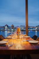 un lungo tavolo di legno con bicchieri da vino e una lampada di Harbor Hotel & Casino Curacao a Willemstad