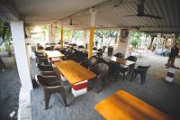 an empty restaurant with wooden tables and chairs at Gokul farm house in Sasan Gir