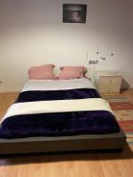 a bed with a purple blanket on it in a room at chambre violette coté aéroport calme charmante in Pusignan