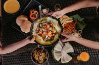 a group of people holding utensils around a plate of food at The Regalia Resort in Mandrem