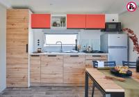 a kitchen with red cabinets and a wooden table at Camping La Mignardière in Ballan-Miré