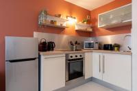 a kitchen with white cabinets and an orange wall at Vieux Lille -Nice studio neat and fully equipped ! in Lille