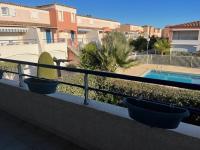 a balcony with two pots on a railing with a swimming pool at Appartement Cap d&#39;Agde, 2 pièces, 4 personnes - FR-1-749-37 in Cap d&#39;Agde