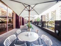 ログローニョにあるMercure Carlton Riojaのパティオに置かれたテーブルと椅子、そして傘