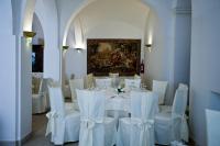 uma sala com uma mesa com cadeiras brancas e uma pintura em Hotel Relais dei Normanni em Monte SantʼAngelo