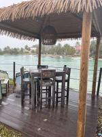 een houten tafel en stoelen onder een rieten paraplu bij ocean view, on the beach. in Le Gosier