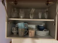 a cupboard filled with dishes and cups and plates at CASA COLIVING avec chambre salle de bain individuelles privatives in Saint-Pierre