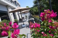 Un patio con flores rosas y una sombrilla. en Vela Verde Hotel &amp; SPA, en Yalova