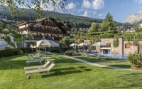 un complejo con una fila de sillas blancas y una piscina en Hotel Angelo Engel, en Ortisei