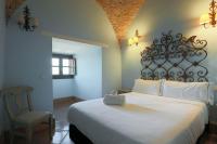 a bedroom with a large white bed and a chair at Hotel Tugasa Castillo de Castellar in Castellar de la Frontera