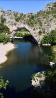 a bridge over a body of water next to a beach at Le Planzollais in Planzolles