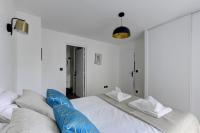 a white bedroom with a large bed with blue pillows at 322 Suite Fes - Superb apartment in Suresnes