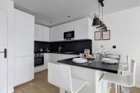 a kitchen with white cabinets and a black table and chairs at 322 Suite Fes - Superb apartment in Suresnes