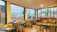 Un restaurante con mesas y sillas y grandes ventanales. en SHARDUL HERITAGE THE RESORT, en Mahabaleshwar