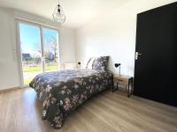 a bedroom with a bed with a floral bedspread and a window at La belle des champs in Luzillé