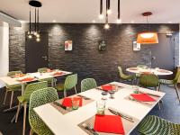 uma sala de jantar com mesas brancas e cadeiras verdes em ibis budget Poitiers Site du Futuroscope em Chasseneuil-du-Poitou