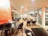uma sala de jantar com mesas, cadeiras e escadas em ibis budget Poitiers Site du Futuroscope em Chasseneuil-du-Poitou