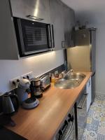 a kitchen counter with a sink and a microwave at Appartement de charme et jardin in Bihorel