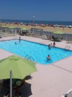 ein Swimmingpool mit einem grünen Sonnenschirm und Menschen darin in der Unterkunft Fish Tales Boardwalk Inn &amp; Ocean Mecca Motel in Ocean City