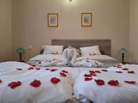 2 camas con pétalos de rosa roja en Hotel Unicornis, en Eger