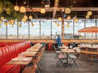 a restaurant with tables and chairs and a man standing in the background at Eklo Paris Expo Porte de Versailles in Vanves