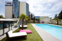 a swimming pool with chaise lounge chairs next to a building at Hotel Palladia in Toulouse