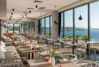 Le Meridien Bodrum Beach Resort في بوغازيتْشي: مطعم مع طاولات وكراسي وإطلالة على المحيط
