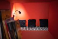 a red wall with three black pillows on a couch at E Fauvette appartement de standing avec terrasse in Épernay