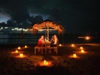 コスゴダにあるOruwa Turtle Beach Villaの夜のビーチで傘の下に座っている二人