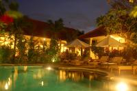 un complejo con piscina con sillas y sombrillas en Gunakaya Homestay, en Sanur