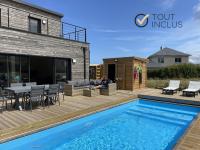 a deck with a swimming pool next to a house at TY COAT - Maison neuve avec vue mer, piscine et bain nordique in Saint-Pabu