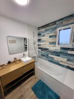 a bathroom with a sink and a tub and a window at TY COAT - Maison neuve avec vue mer, piscine et bain nordique in Saint-Pabu