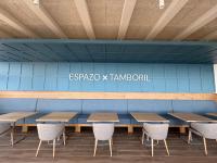 Una cafetería con mesas y sillas de madera y una pared azul. en ESPAZO NATURE, en Carballo