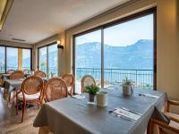 Um restaurante com mesas e cadeiras e uma grande janela. em Hotel San Pietro em Limone sul Garda