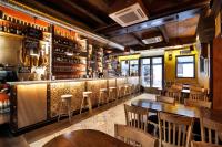 Un restaurante con un bar con mesas y sillas de madera. en Apartamentos El Tiempo, en Madrid