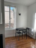 a black table and chairs in a room with a window at Charmant 2 pièces proche RER B direction Paris in Fontenay-aux-Roses