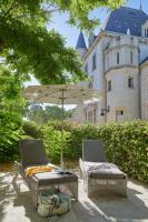 two chairs and an umbrella in front of a castle at Château Les Carrasses in Capestang