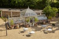 a greenhouse with tables and chairs in a garden at Château Les Carrasses in Capestang