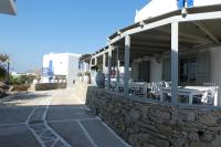 a patio with tables and chairs on a stone wall at Cute double storey condo I Pool & Beach in Mýkonos City