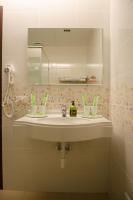 a bathroom sink with a mirror and green toothbrushes at Apple Tree Bed and Breakfast in Hualien City