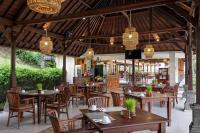 a restaurant with wooden tables and chairs and chandeliers at Santi Mandala Villa & Spa in Sukawati