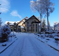 a snow covered road in front of a house at Malachit Karpacz SPA Hotel in Karpacz