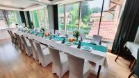 a long table with white tables and chairs in a room with large windows at Malachit Karpacz SPA Hotel in Karpacz