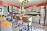 a kitchen with white cabinets and a bar with stools at Villa mimosas in Brech
