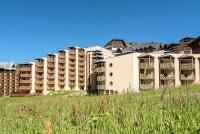 an apartment building with tall grass in the foreground at Résidence Les Temples du Soleil - maeva Home - 2 Pièces 5 Personnes Sélect 52 in Val Thorens