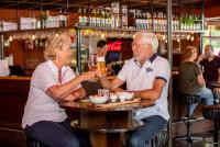 twee mensen aan een tafel met een glas wijn bij Recreatiepark De Tien Heugten in Schoonloo