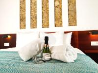a bottle of wine and a glass on a bed at Vejerísimo Casa Boutique in Vejer de la Frontera